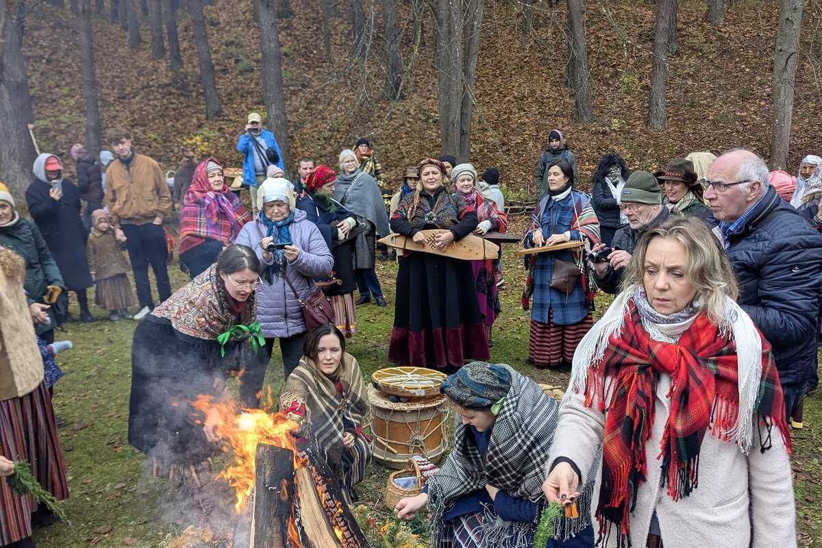 Visitors in folk dress around a Mārtiņdiena bonfire at the Latvian Ethnographic Open-Air Museum, Riga.