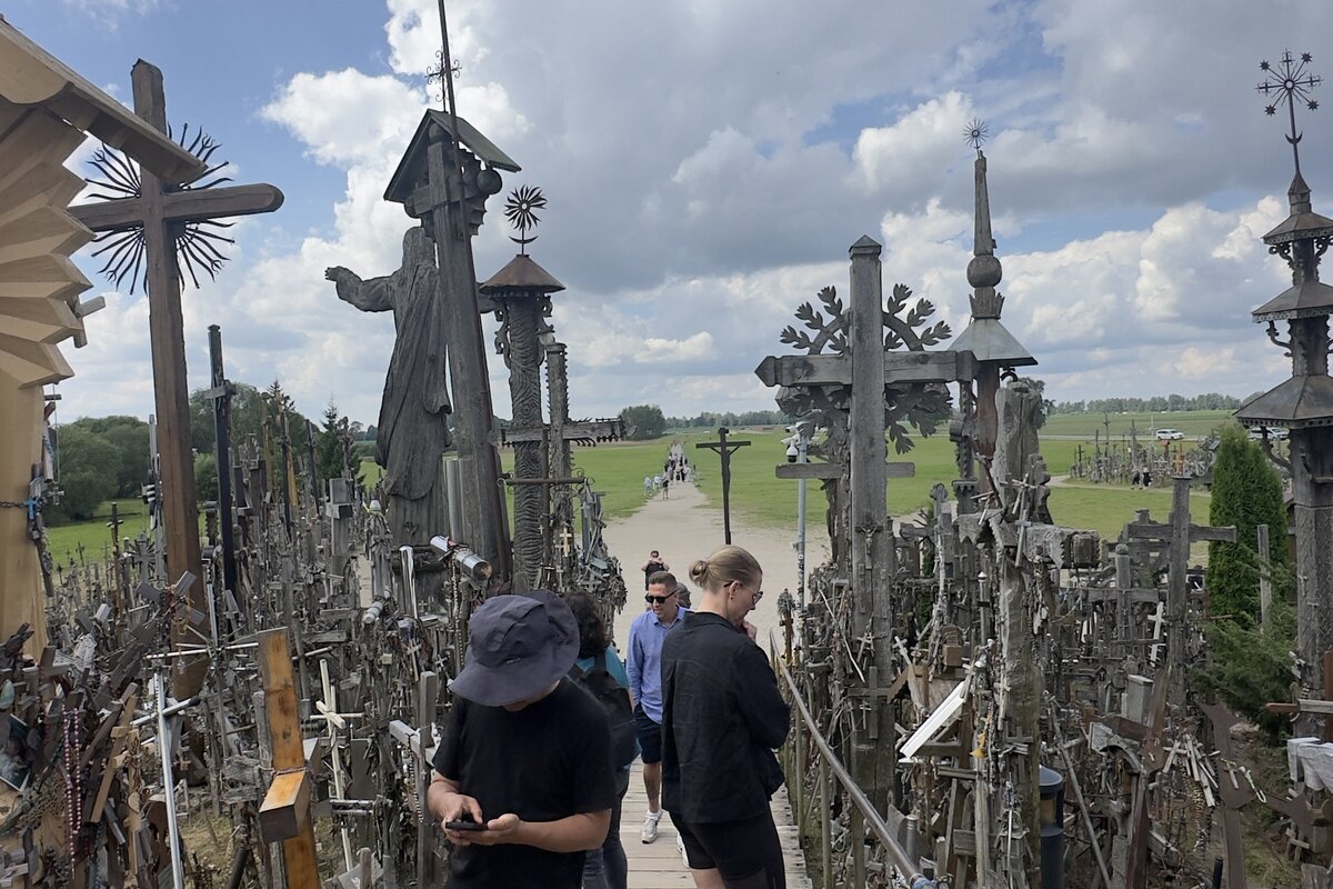 The Hill of Crosses (Kryžių kalnas) near Šiauliai, Lithuania — boardwalk path with the standing Jesus statue and crosses in every direction.