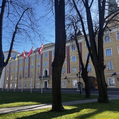 Pils laukums in spring with castle flags between bare trees, Riga, Latvia