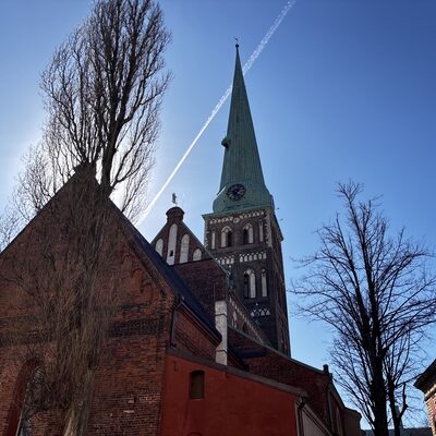 The St James's Cathedral spire from below with a contrail in the sky, Riga, Latvia