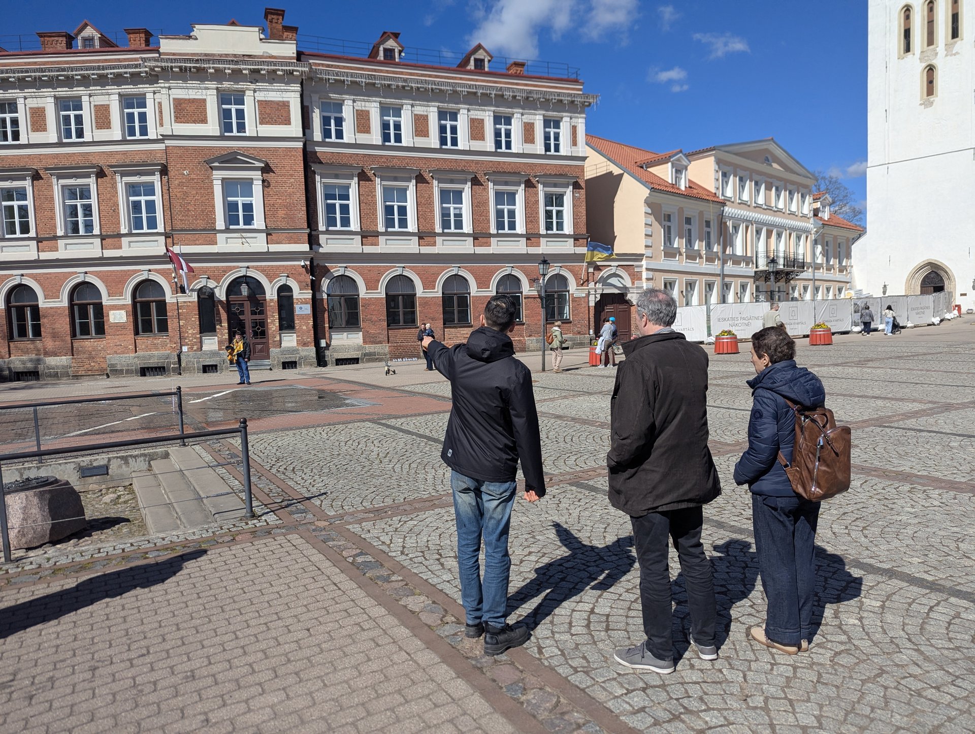 Cēsis senamiesčio centrinė aikštė su nedidele ekskursijų grupe, grindiniu ir istoriniais pastatais, Latvija
