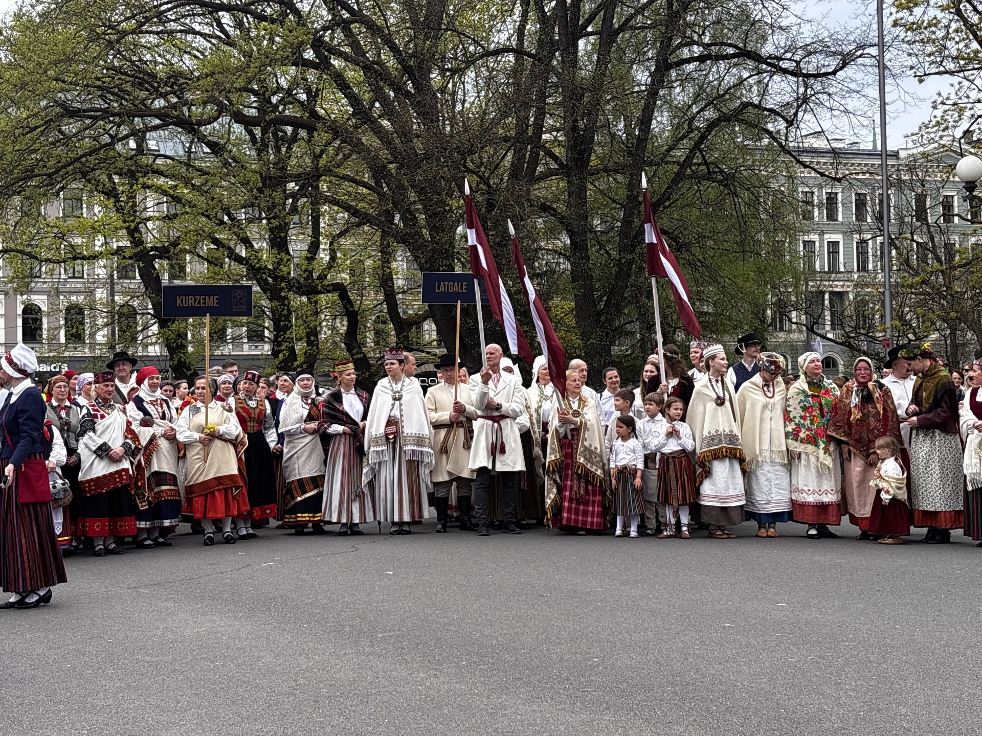 People in Latvian folk dress with Latvian regional flags during Independence Day celebrations in Riga