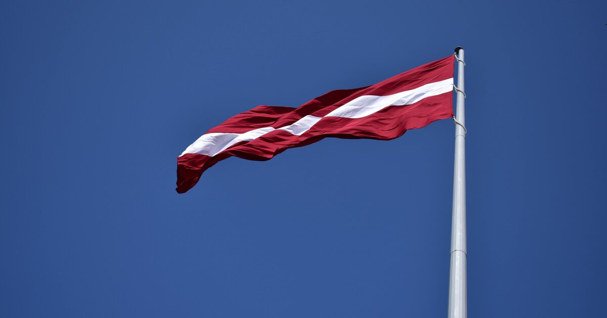 Läti lipp — karmiinpunane valge ribaga — sinise taeva vastu.